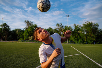 Young male soccer player juggles a ball with his head on a soccer field © bo.kvk