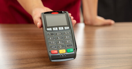 Cashier offering POS terminal for payment with credit card.