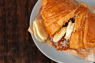 Half cut croissant with chocolate paste and sliced bananas
