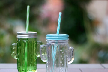 Two glasses, shaped like cacti, filled with cold water and served in a garden. Selective focus.