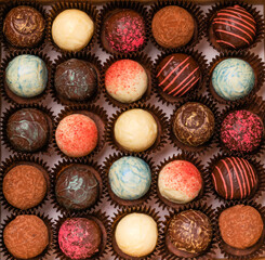 Chocolate candies truffle from various colored chocolate toppings close-up top view. Dessert holiday concept