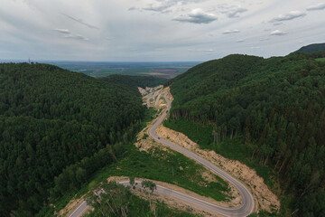 Fototapeta premium Aerial top vew of winding road in the mountains, drone shot. Altai Krai, Western Siberia, Russia. Road to Resort town Belokurikha 2