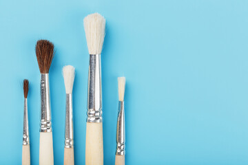 Brushes for drawing made of natural wood and wool. on a blue background.