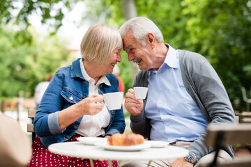 Happy senior couple in love sitting outdoors in cafe, having fun.