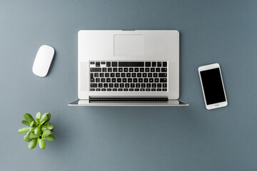 Office desktop with laptop, smart phone and computer mouse on gray table. Business background. Flat lay