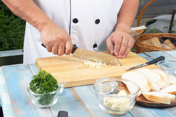 Chef chopping garlic for cooked Garlic bread