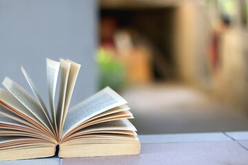 Open book on a table in a yard. Selective focus.
