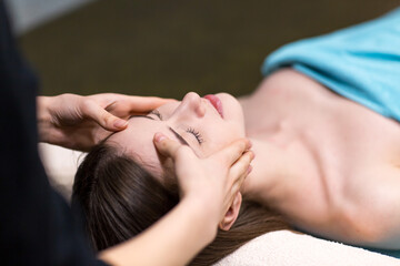 Young beautiful woman receiving head face massage in beauty spa