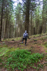 Fototapeta premium Travel woman with backpack. Enjoying nature sunset. Relaxing in park during wet weather. Trekking concept