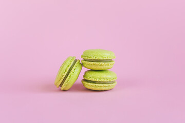 Tasty french light green macaroons on a pink pastel background.
