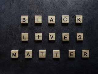 Inscription of wooden letters black lives matter on a dark background.