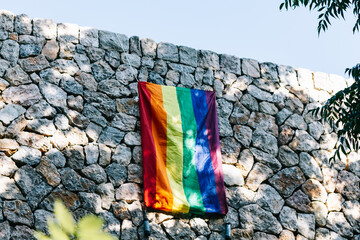 A Gay flag hanging from stone wall in rural area