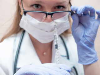 Nurse holding syringe for vaccination. Caucasian woman. CIS region medicine.