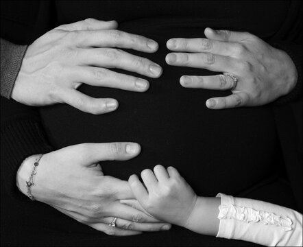 Hands of mom, dad and baby on the belly of a pregnant mom. The image of a happy family.