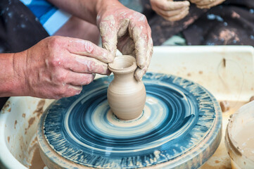 Fototapeta na wymiar The potter makes pottery dishes on potter's wheel.