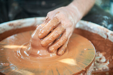 The potter makes pottery dishes on potter's wheel.