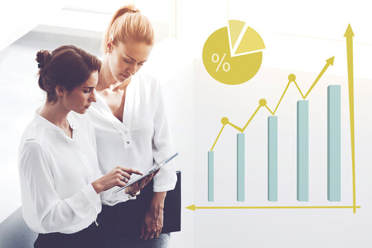 Two female employees monitoring financial income of enterprise company via touch pad standing in office.Women successful economists are using digital tablet analysing work progress. Infographic graphs - Powered by Adobe