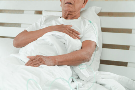 Sad senior man lying on the hospital bed and with a nasal breathing tube for treatment respiratory. Concept of Health care for the elderly, quarantine coronavirus (COVID-19)