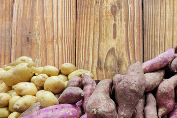 Sweet potato and English potato on aged wooden background