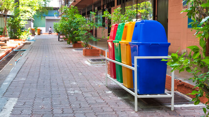 Fototapeta na wymiar Perspective and side view of multicolored garbage bins on brick pavement in the school