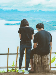 Back view of lovers enjoy with beautiful scenery view of nature with a large reservoir above the Srinagarind Dam at Rai Ya Yam view point in Si Sawat District, Kanchanaburi Thailand.