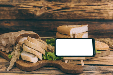 Mock up smartphone on background with fresh bread on a wooden background.