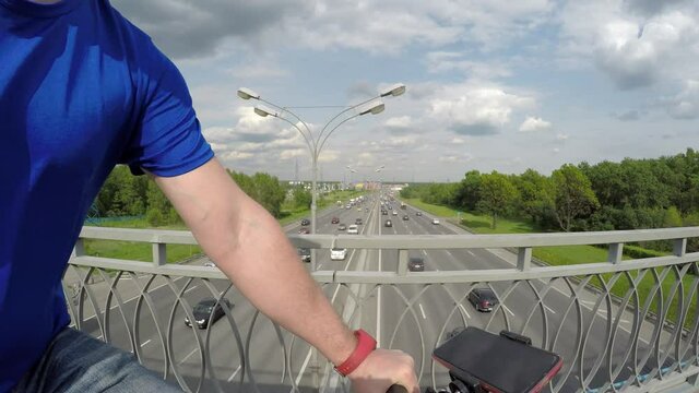 Fish eye view of man riding bike on bridge above Moscow ring highway MKAD. Travelling by bike.