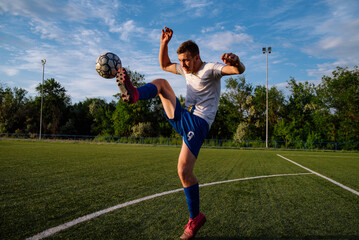 Young male soccer player juggles a ball on a soccer field. © bo.kvk