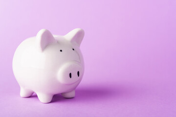 Front small white fat piggy bank, studio shot isolated on purple background and copy space for use,...