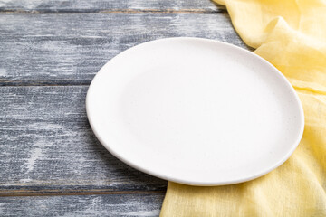 Empty white ceramic plate on gray wooden background. Side view.