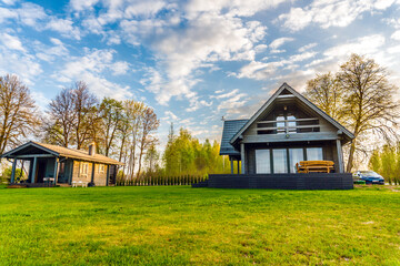 Luxurious country wooden house against trees and beautiful clouds. Cottage.