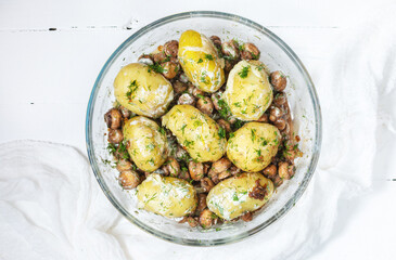 Roasted young potatoes in glass baking dish with mushrooms.