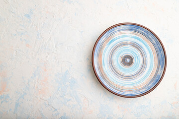 Empty blue ceramic plate on white concrete background. Top view, copy space.