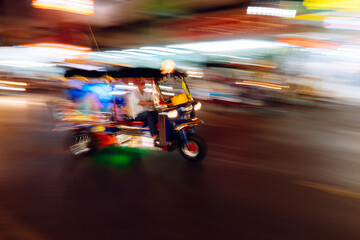The tuk-tuk is passing by at a blurred speed, blurred images taking pictures with slow shutter speeds. - obrazy, fototapety, plakaty