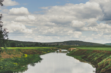 River side landscape with bridge over the river and fluffy clouds on a bright blue sky in a rural Moldovan setting