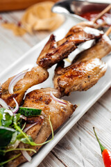 Quail barbecue skewers with salad and red sauce
