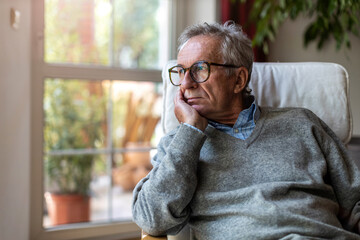 Senior man looking out of window at home
 - Powered by Adobe