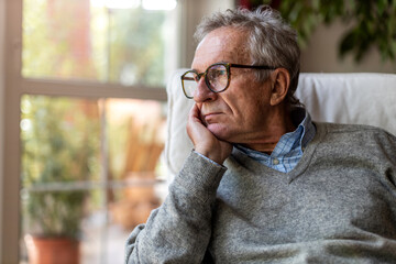 Senior man looking out of window at home
