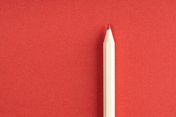 Wooden red pencil on red background