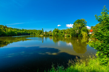 Small lake and fish pond near Mnisek pod Brdy chateau. Summer day with blue sky
