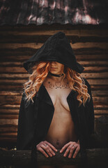 Girl in black underwear and a black cloak in the forest.