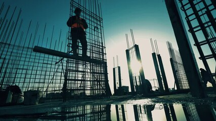 Construction industry, construction project, building process during sunset. Constructors are building a metal framework of a building