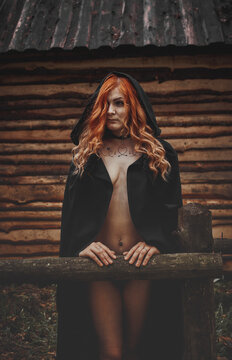Girl in black underwear and a black cloak in the forest.