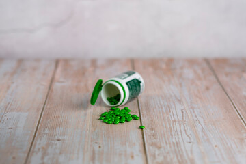 Home therapy. Round green vitamin pills on wooden table