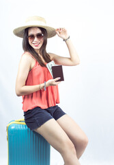 Portrait of woman wearing sunglasses, hat and holding money and passport on white background.