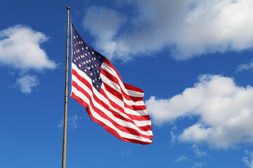 a bright flowing waving american flag on a sunny day with a few white clouds