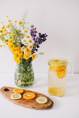 Summer concept. Bouquet of wild natural flowers. Homemade lemonade with orange and lemon. Healthy  fresh cool beverage 