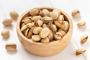 Pistachio nuts in a wooden bowl on white background
