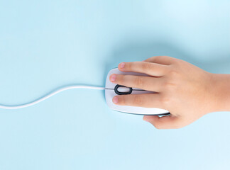 Child's hand holds a computer mouse on a blue background.