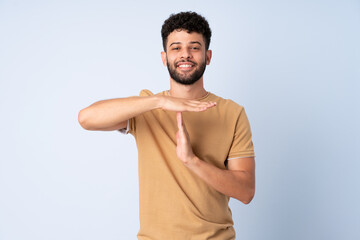 Young Moroccan man isolated on blue background making time out gesture